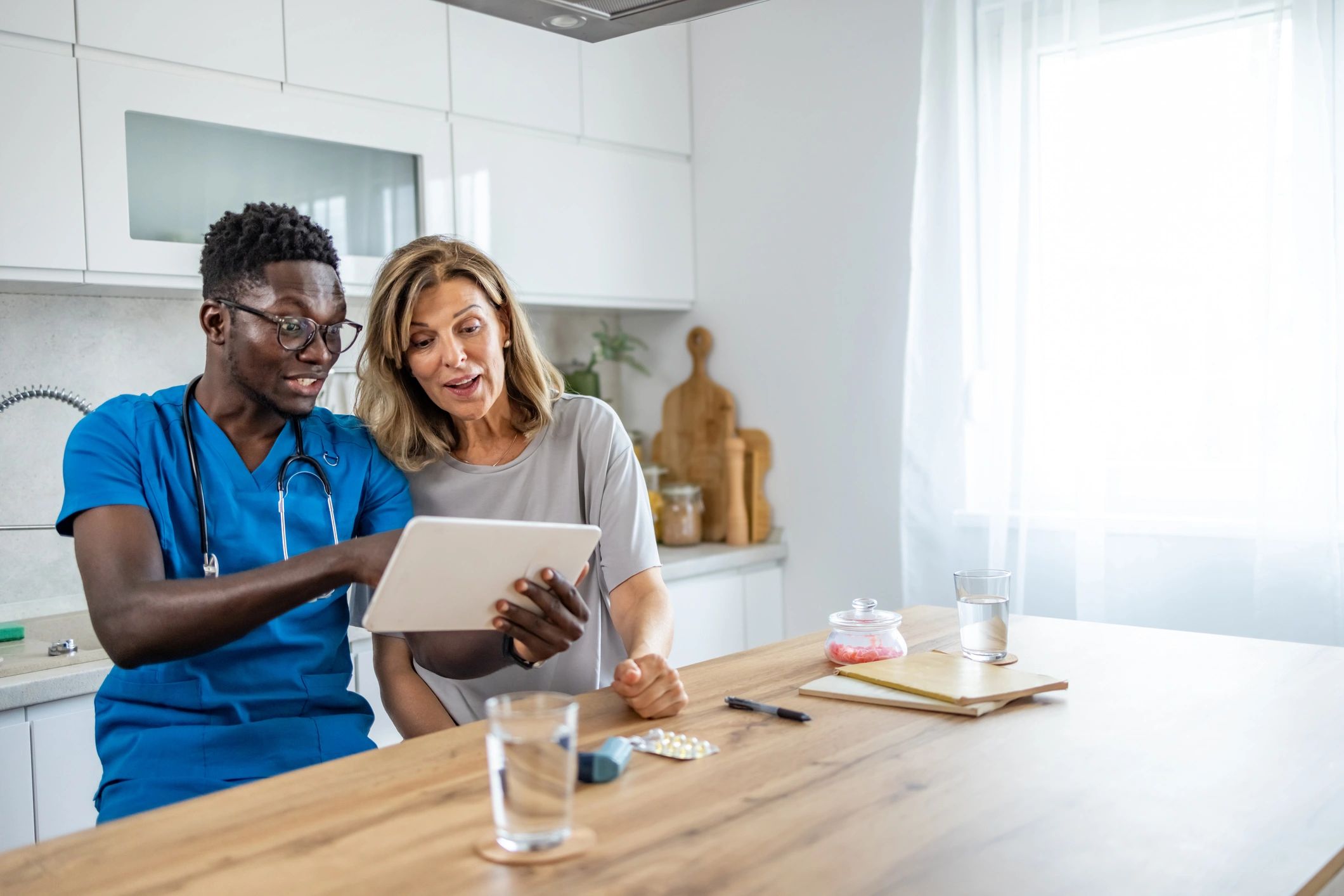 Home Caregiver showing tablet to senior woman at her house