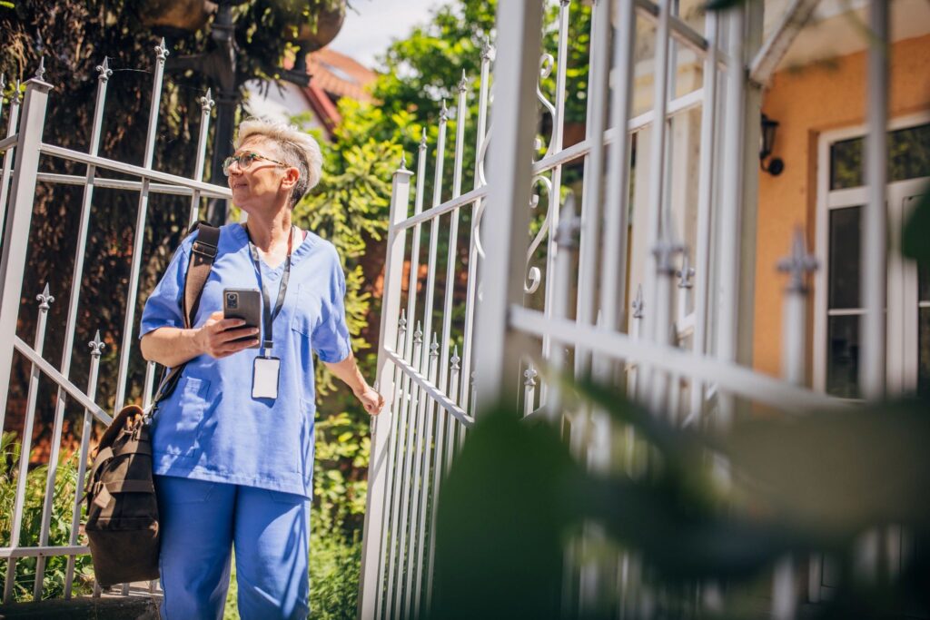 Nurse holding a phone while opening an ornate gate