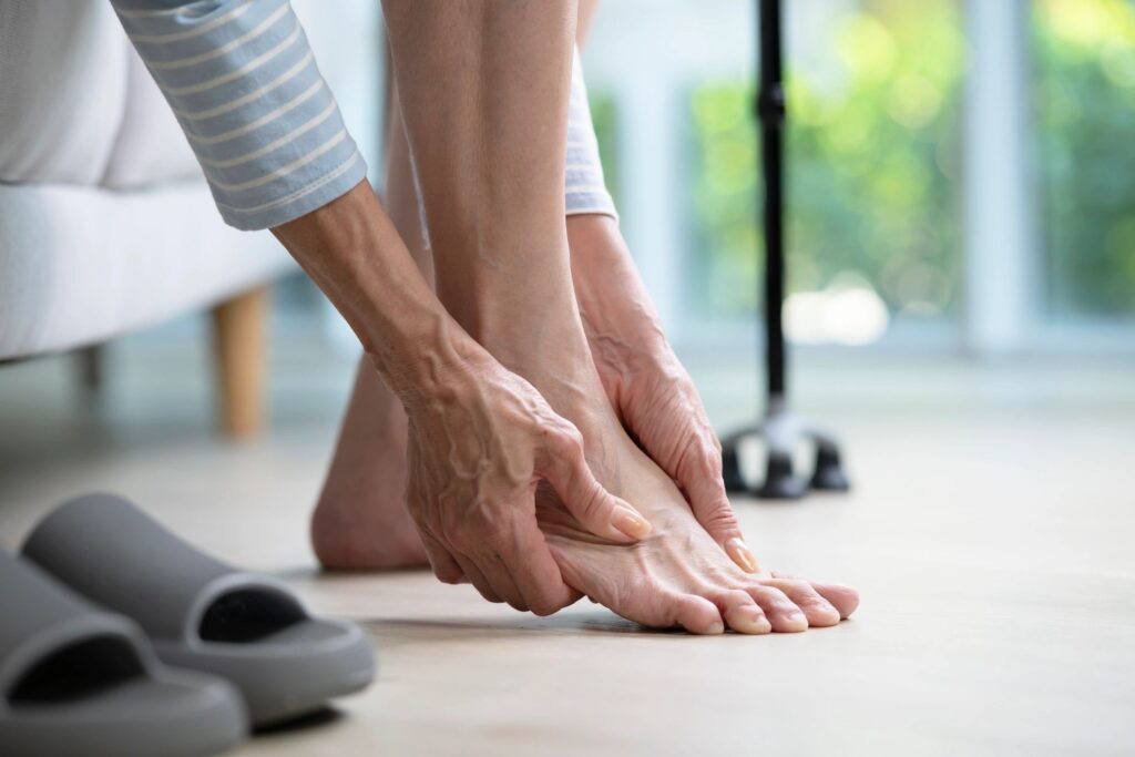 Senior woman suffering from pain in ankle at home.