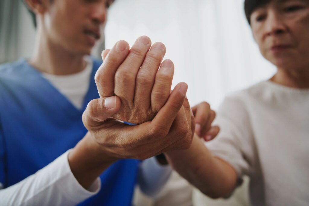 Physical therapist examining a mature woman’s hand during therapy.