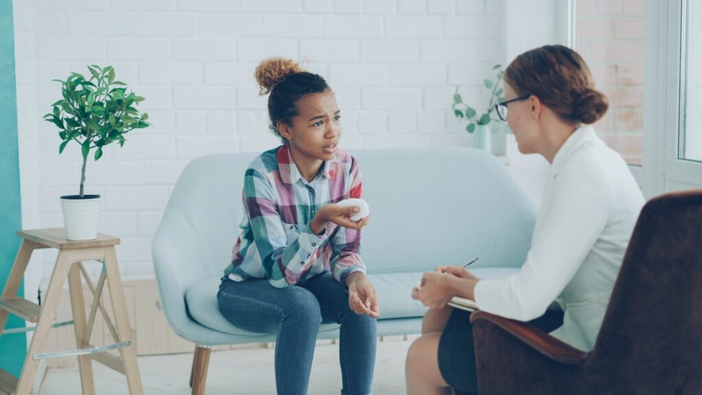 Healthcare provider talking to a young girl on couch.